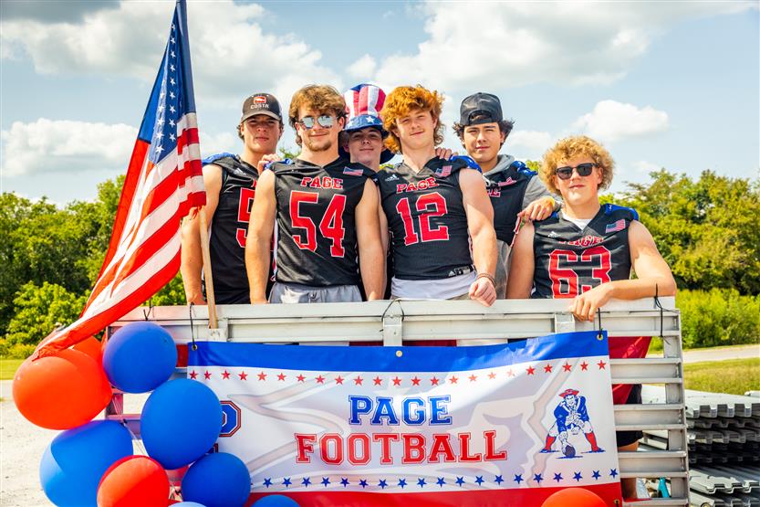 Boys in football jerseys smile on a float